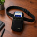 Agoz black waist belt holster holding a myPOS handheld payment terminal on a wooden desk, with adjustable strap and buckle.