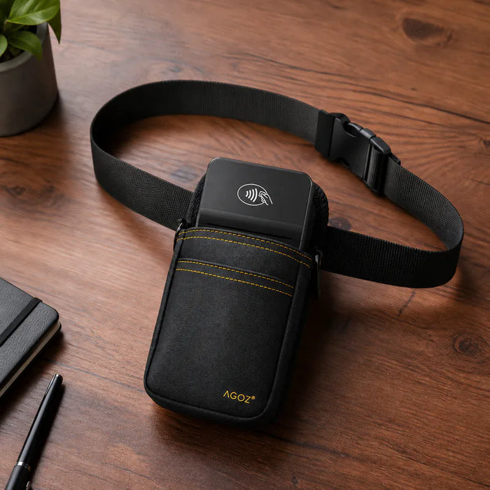 A black AGOZ POS waist bag with a built-in black rectangular device, shown on a wooden tabletop with a plant and notebook in the background.