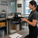 Visitor services employee printing a guest badge from a Seiko SII printer on an Agoz pole-mounted shelf.