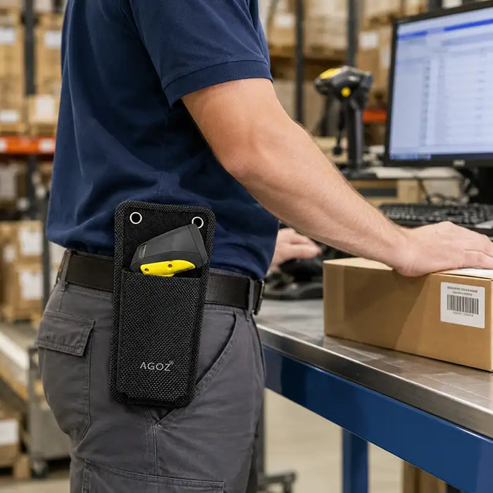 Close-up of a black Agoz waist belt scanner case carrying a Cognex device at a warehouse workstation.