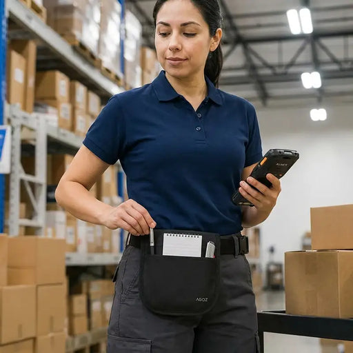 Warehouse employee wearing an Agoz utility apron while holding an Almex mobile computer for inventory and fulfillment work