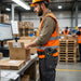 CipherLab mobile computer with pistol-grip waist belt holster worn by a warehouse worker packing cartons at a shipping workstation.