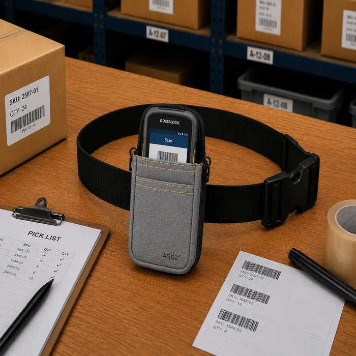 Gray AGOZ waist belt scanner case holding a Datalogic mobile computer on a warehouse packing table with a pick list, labels, and shipping supplies.