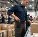 Warehouse worker using AgozTech black holster case with Zebra handheld mobile computer at packing station