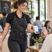 Café worker using a Stripe Reader S700 for mobile payment while wearing an empty Agoz black canvas case on her waist belt.