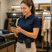 Retail clerk using an Almex mobile computer with rugged belt case attached at the waist in a clothing store checkout area.
