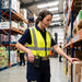Warehouse worker using a headset with a Honeywell Voice terminal carried in an AgozTech belt clip case while picking inventory in a warehouse storage aisle.